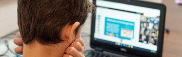 Young boy staring at laptop screen at home.