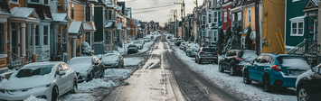 Snowy residential street with small homes.