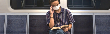 Man sitting and reading on a subway train.