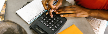 Woman adding up household budget on calculator.