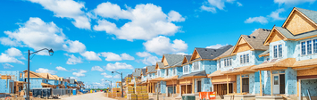 Row of homes under construction along a road.