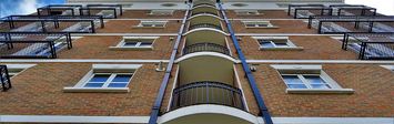 View looking up the face of an apartment building, towards the sky.