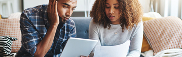 Couple considering bills in living room.