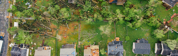 View of houses with storm damage and fallen trees.