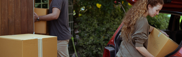 Young couple loading possessions into car.