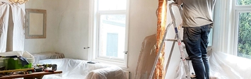 Man on ladder in apartment being renovated.