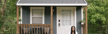 Woman sitting on front porch of tiny single-family home.
