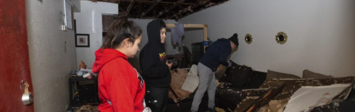 Family standing inside storm-damaged apartment.