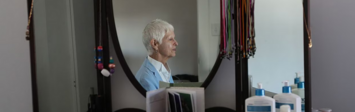 View of older woman sitting by mirror.