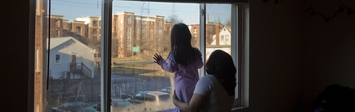 Family looking out of a window in a city
