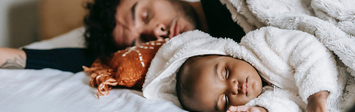 Father and baby napping on bed.