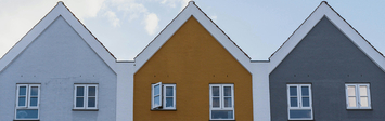 Facades of three townhouses with pitched roofs.