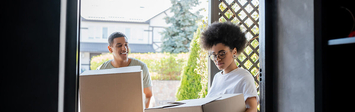 Couple carrying boxes into a house.