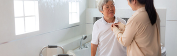 Caregiver helping older adult get dressed.