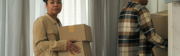 Two people moving boxes out of a home.