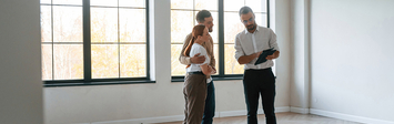 Young couple with a realtor in an empty home.
